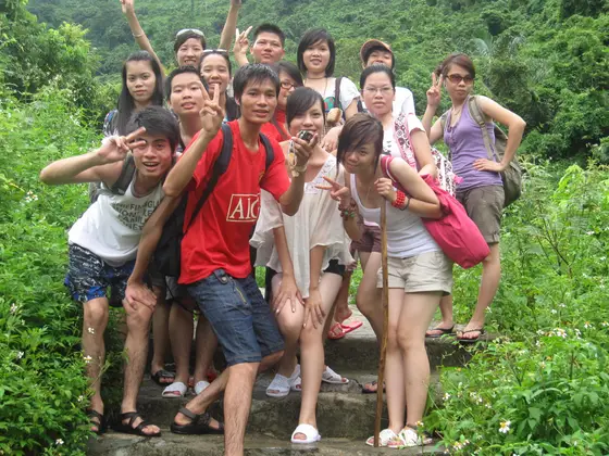 Nhóm người tạo dáng trên lối bậc đá giữa cây cỏ xanh, một người mặc áo đỏ ở phía trước.